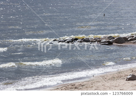 Serene seaside view with soft waves crashing on rocks and a sandy beach Serene seaside view with soft waves crashing on rocks and a sandy beach 123766009