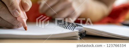 Closeup of hand highlighting notes in a spiral notebook Closeup of hand highlighting notes in a spiral notebook 123766334