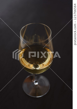 White wine in a wineglass on black oak table with copy space 123766564