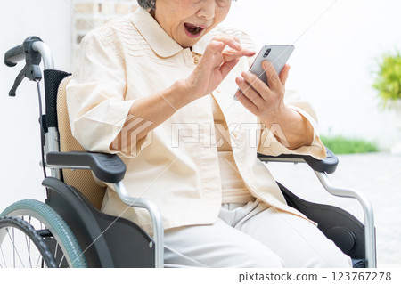 Senior woman in a wheelchair operating a smartphone 123767278