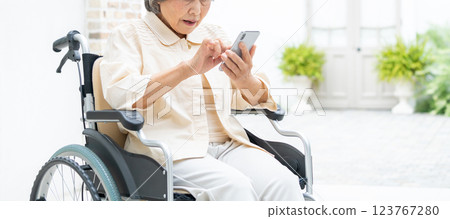 坐在輪椅上操作智慧型手機的高級女性 123767280