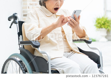 坐在輪椅上操作智慧型手機的高級女性 123767281