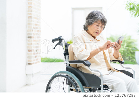 坐在輪椅上操作智慧型手機的高級女性 123767282