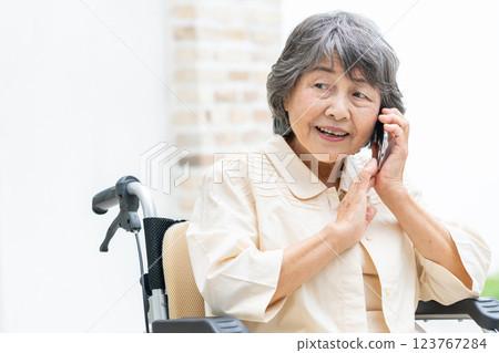 Senior woman in a wheelchair making a phone call Senior woman in a wheelchair making a phone call 123767284
