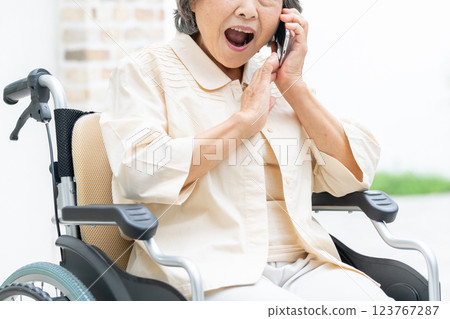 Senior woman in a wheelchair making a phone call 123767287