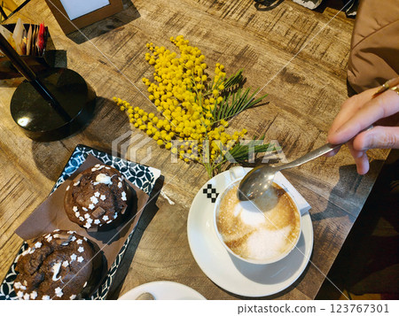 Twig of mimosa flowers on a table with coffee and muffins. Women day. Twig of mimosa flowers on a table with coffee and muffins. Women day. 123767301