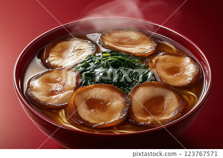 A warm bowl of ramen is presented, featuring rich, savory broth topped with tender pork slices and fresh green vegetables. Steam rises, highlighting the dishs inviting aroma. 123767571
