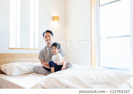 Parent and child sitting on bed 123768187