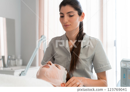 Professional masseuse fixing sheet mask on woman's Professional masseuse fixing sheet mask on woman's 123769041