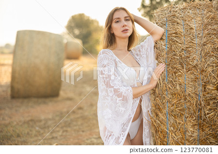 Young woman in negligee stands in hay field Young woman in negligee stands in hay field 123770081