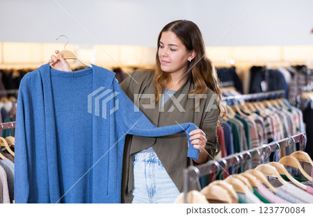Young woman choosing warm cardigan in store Young woman choosing warm cardigan in store 123770084