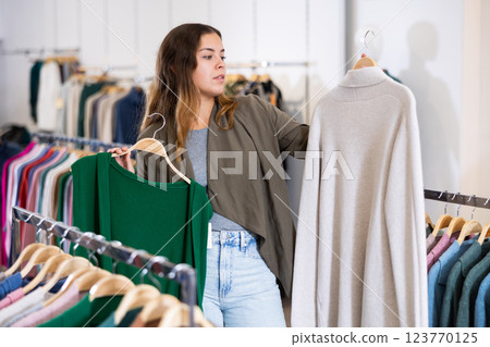 Young woman choosing knitted vest or cardigan 123770125