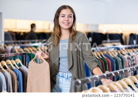 Young woman choosing knitted sweater in store Young woman choosing knitted sweater in store 123770141