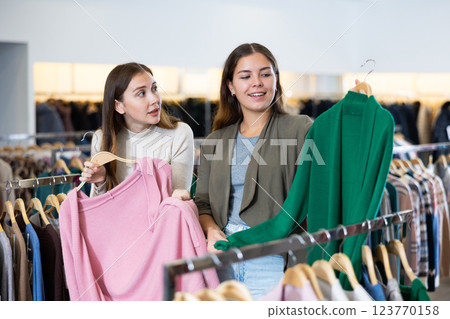 Female friends choosing warm cardigan in store Female friends choosing warm cardigan in store 123770158