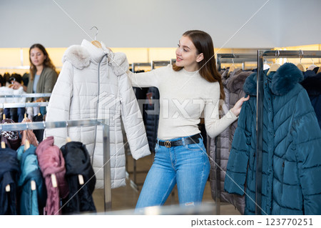 Young woman choosing insulated coat in store 123770251