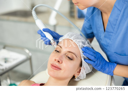 Adult woman cosmetologist doing cleansing procedure to young woman Adult woman cosmetologist doing cleansing procedure to young woman 123770265