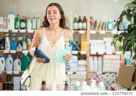 Young woman chooses cleaning spray in store Young woman chooses cleaning spray in store 123770271