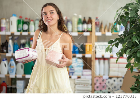Girl in a summer dress chooses feminine pads in supermarket 123770313