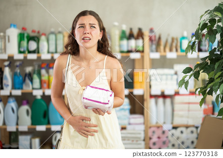 Woman with period pain choosing sanitary pads in store Woman with period pain choosing sanitary pads in store 123770318