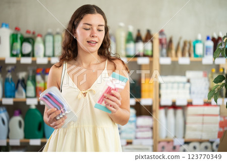 Girl carefully selects razor for shaving in household goods department of supermarket Girl carefully selects razor for shaving in household goods department of supermarket 123770349