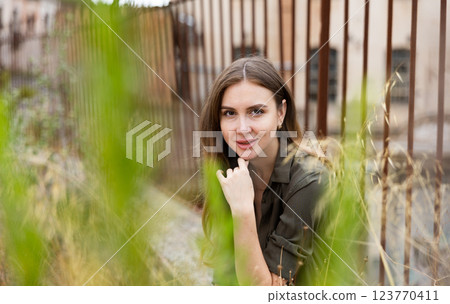 Woman posing near fence against abandoned building Woman posing near fence against abandoned building 123770411