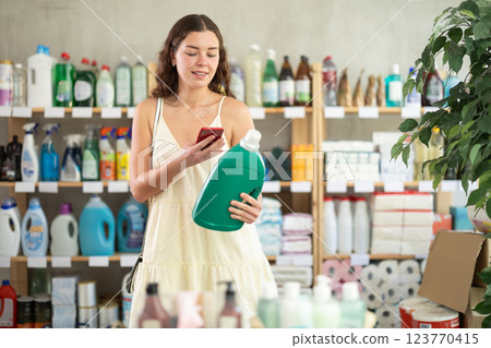Young female shopper scanning barcode on bottle of fabric softener Young female shopper scanning barcode on bottle of fabric softener 123770415