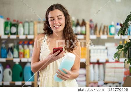 Checking expiration date of shampoo or shower gel - female shopper scans QR code on label of shampoo using smartphone 123770496