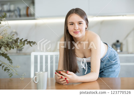 Young woman reading message in kitchen at home Young woman reading message in kitchen at home 123770526
