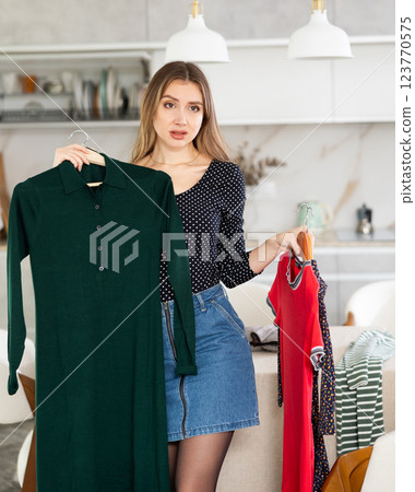 Young upset woman choosing which dress to wear 123770575