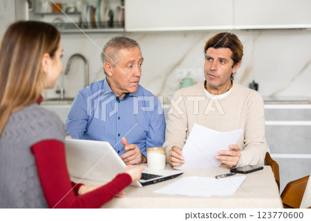 Two men listen attentively to saleswoman talking about the advantages of taking out microloan from credit institution 123770600