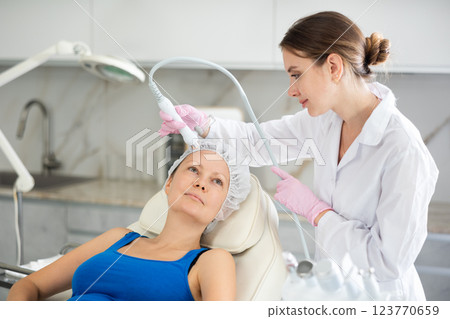 Young doctor use macromolecule atomizing pen for atomized nutrients to supplement and face skin nutrition for woman in cosmetology clinic. Moisturizing and rejuvenating hardware procedures Young doctor use macromolecule atomizing pen for atomized nutrients to supplement and face skin nutrition for woman in cosmetology clinic. Moisturizing and rejuvenating hardware procedures 123770659