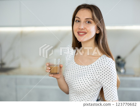 Portrait of cheerful contented woman with cup of cocoa in her hands in modern kitchen 123770682