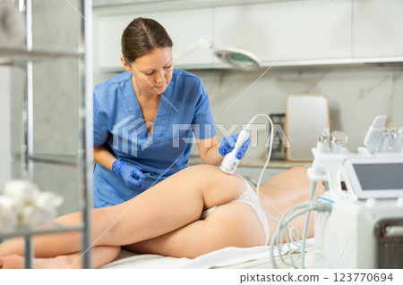 Adult woman cosmetologist performs rejuvenating procedure on butt of young woman 123770694