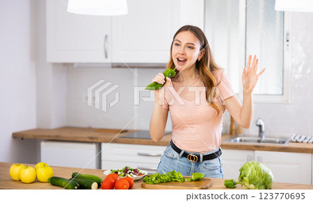 Woman having fun while cooking salad at home 123770695