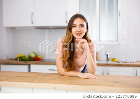 Portrait of young woman leaning on kitchen table 123770699