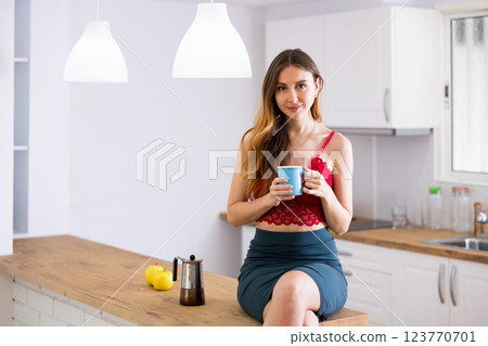 Woman drinking coffee at kitchen in morning 123770701