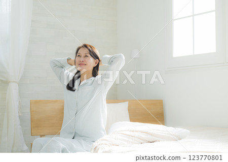 躺在床上伸展身體的老年婦女 躺在床上伸展身體的老年婦女 123770801