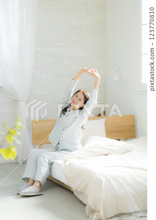 躺在床上伸展身體的老年婦女 躺在床上伸展身體的老年婦女 123770810