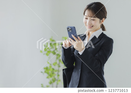 操縱智能手機的衣服的一名婦女 123771013