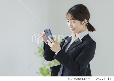 操縱智能手機的衣服的一名婦女 123771015