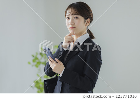 操縱智能手機的衣服的一名婦女 123771016