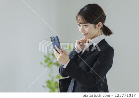 操縱智能手機的衣服的一名婦女 123771017