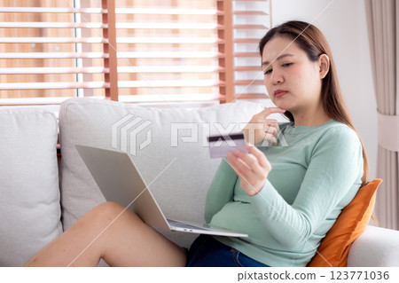 Young asian woman sitting on sofa using laptop computer shopping online with credit card. 123771036