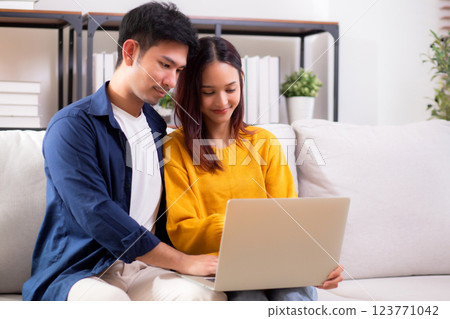 Young asian couple looking on laptop for relax with cozy and contentment sitting on sofa. Young asian couple looking on laptop for relax with cozy and contentment sitting on sofa. 123771042