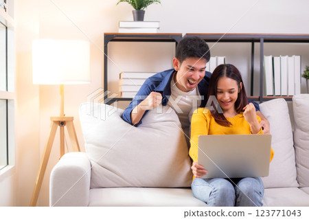 Young asian couple looking on laptop for relax with cozy and success sitting on sofa in living room. Young asian couple looking on laptop for relax with cozy and success sitting on sofa in living room. 123771043
