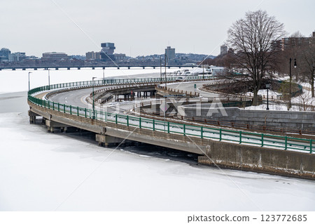 Curve road by the edge of Charles River seen from Long Fellow Bridge in Boston, MA duing winter, Charles River covered in snow and ice 123772685