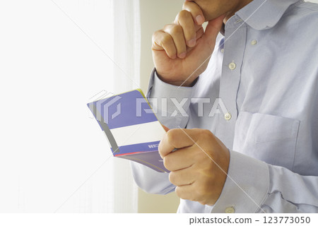 Middle-aged man looking at his savings passbook 123773050