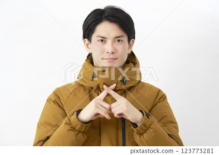 A man wearing a down jacket makes a gesture of the cross on a white background A man wearing a down jacket makes a gesture of the cross on a white background 123773281