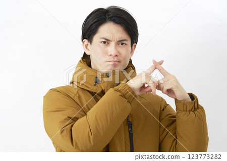 A man wearing a down jacket makes a gesture of the cross on a white background A man wearing a down jacket makes a gesture of the cross on a white background 123773282