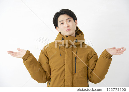 一位穿著羽絨外套的男子驚訝地看著白色背景下的相機 123773300